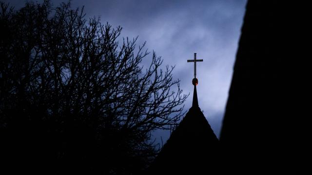 Wolken im Abendhimmel über dem Kreuz auf einem evangelischen Kirchturm