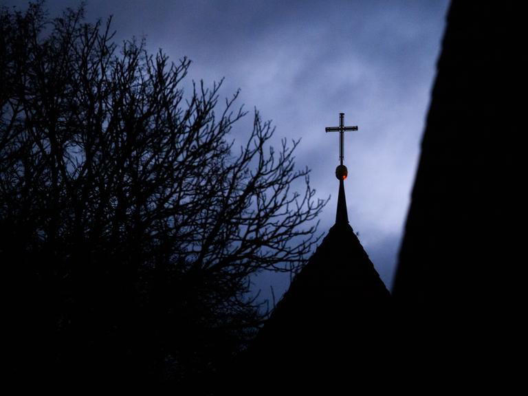Wolken im Abendhimmel über dem Kreuz auf einem evangelischen Kirchturm Wolken im Abendhimmel über dem Kreuz auf einem evangelischen Kirchturm