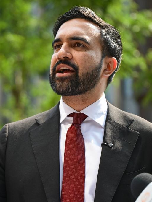Der Bürgermeisterkandidat für New York, Zohran Mamdani, spricht an einem sonnigen Tag mit erhobener Hand  Der Bürgermeisterkandidat für New York, Zohran Mamdani, spricht an einem sonnigen Tag mit erhobener Hand