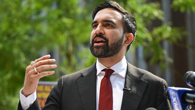 Der Bürgermeisterkandidat für New York, Zohran Mamdani, spricht an einem sonnigen Tag mit erhobener Hand 