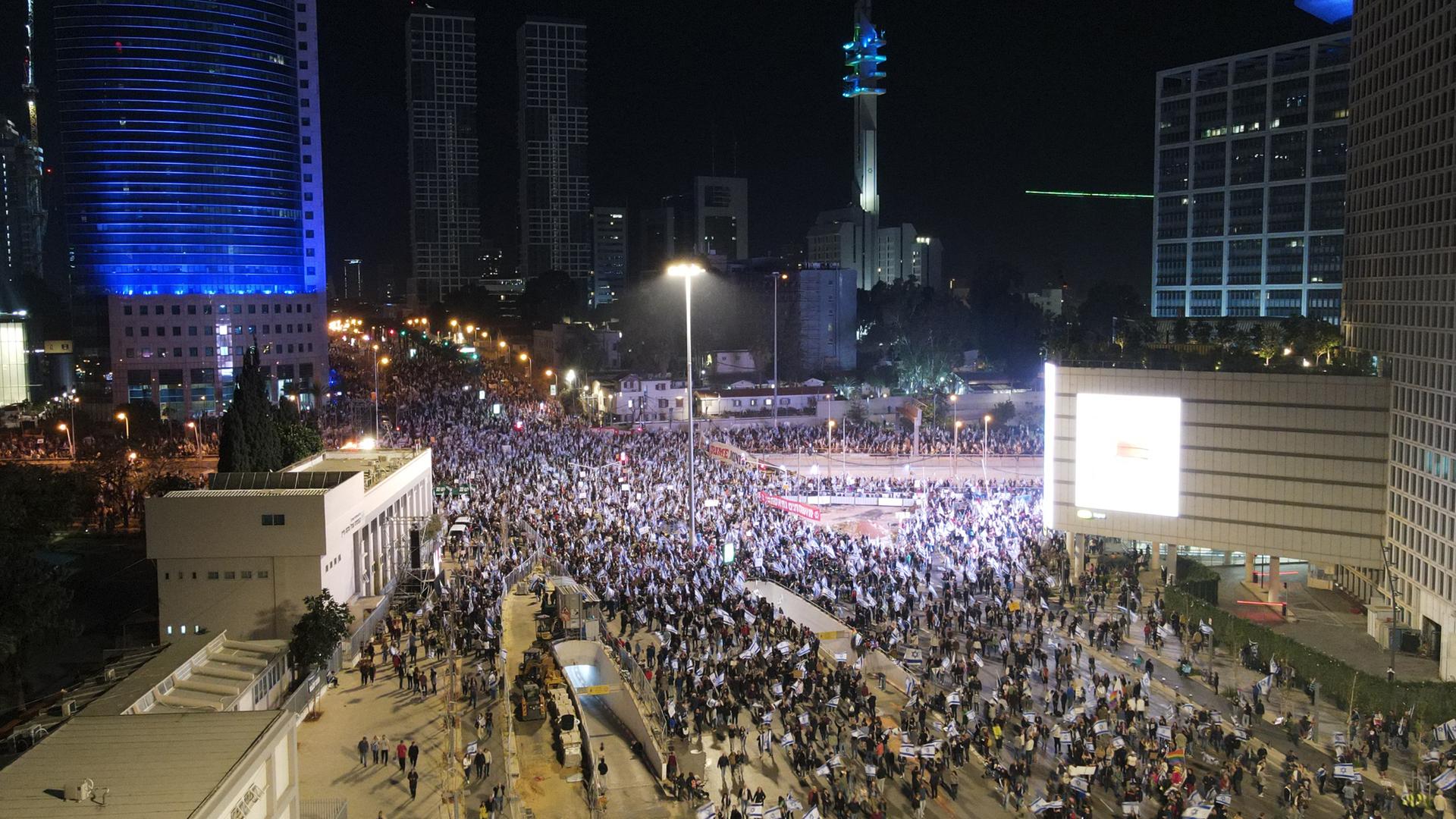 Das Bild zeigt von oben eine große Menschenmenge auf einem Platz in der Nacht.
