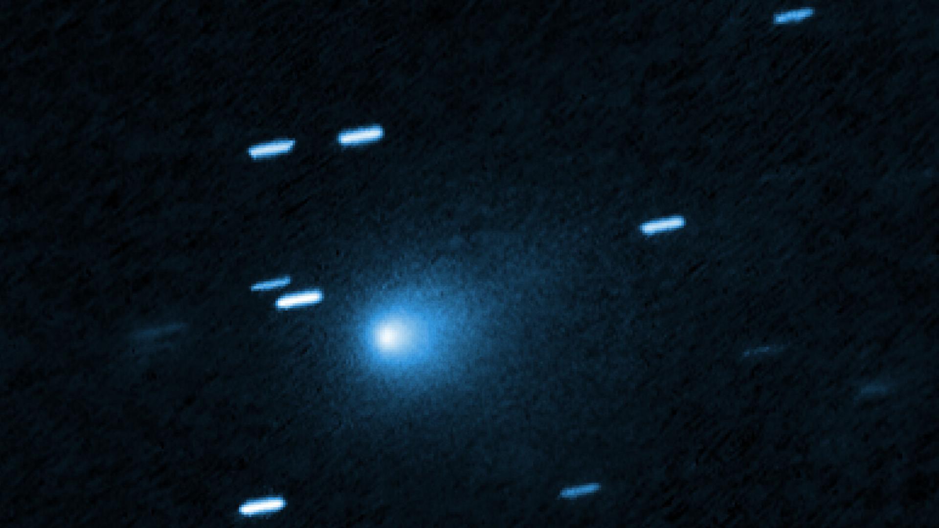 Der interstellare Komet 3I/ATLAS aufgenommen mit dem Hubble Space Teleskop am 21. Juli 2025. Die Aufnahme zeigt vor schwarzem Hintergrund helle Lichtflecken. Ungefähr in der Mitte ist ein größerer Lichtfleck mit Aura. Der interstellare Komet 3I/ATLAS aufgenommen mit dem Hubble Space Teleskop am 21. Juli 2025. Die Aufnahme zeigt vor schwarzem Hintergrund helle Lichtflecken. Ungefähr in der Mitte ist ein größerer Lichtfleck mit Aura.