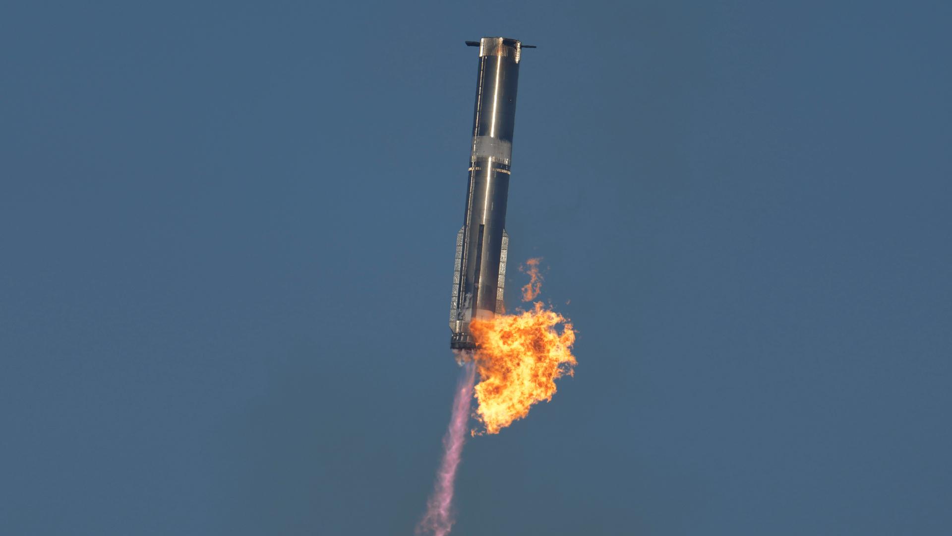 Der untere Teil der Rakete kehrt sicher zur Erde zurück. Flammen schlagen dabei aus dem Raketenkörper. 