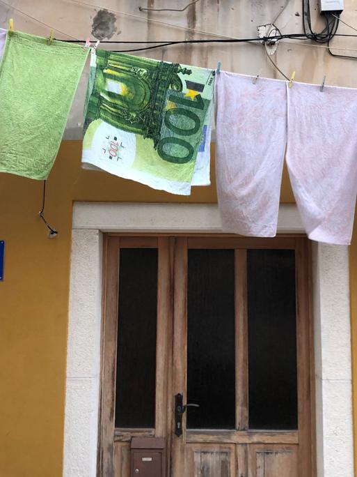Auf eine Wäscheleine hängt eun Handtuch mit Euroschein Motiv
