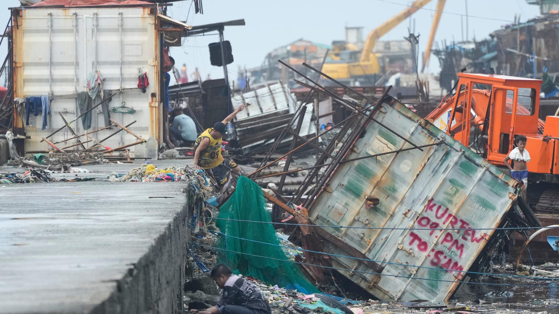 Navotas, Philippinen: Ein Mann springt neben einen Container, der durch den Taifun "Fung-wong" umgestürzt ist.