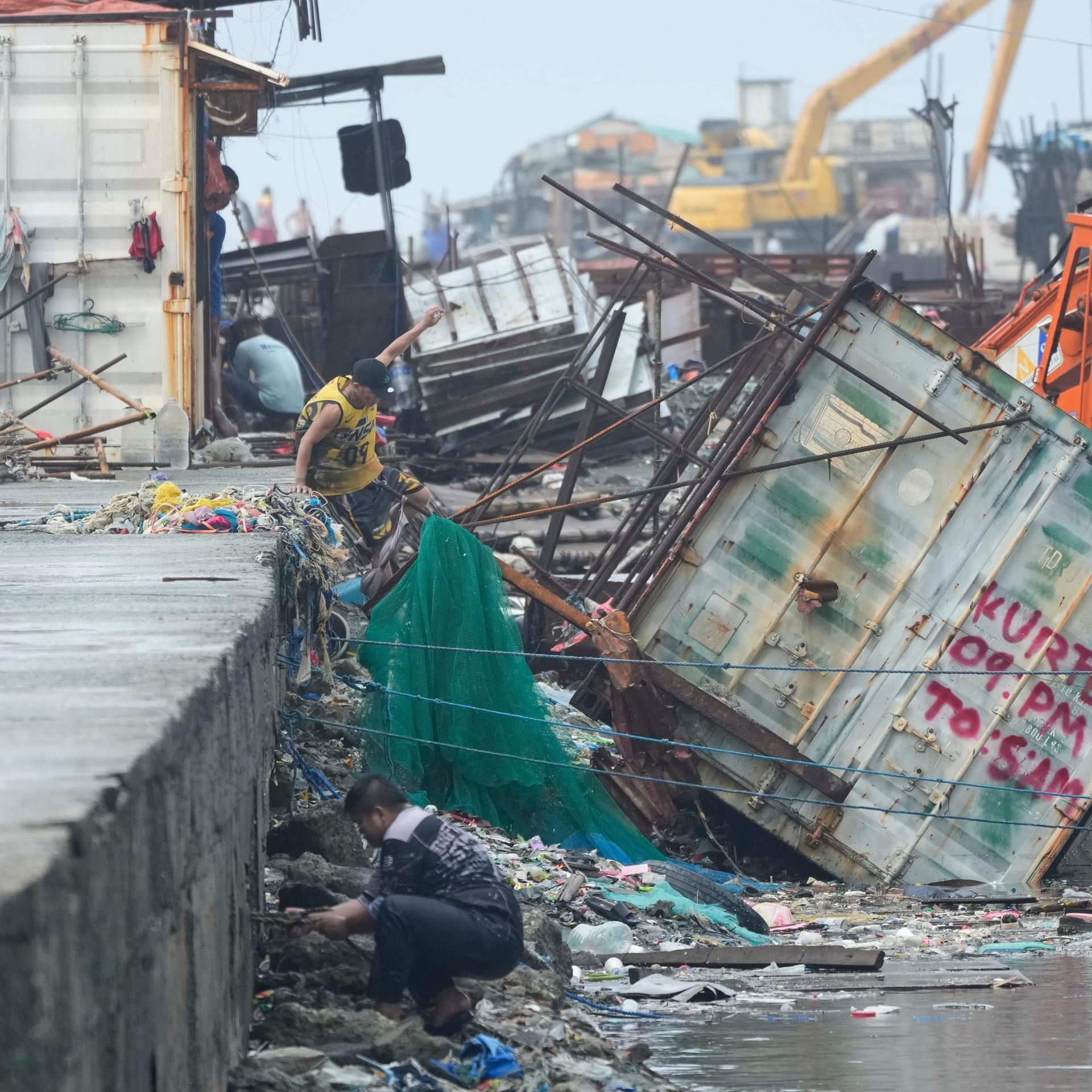 Navotas: Ein Mann springt neben einen Container, der durch den Taifun "Fung-wong" umgestürzt ist.