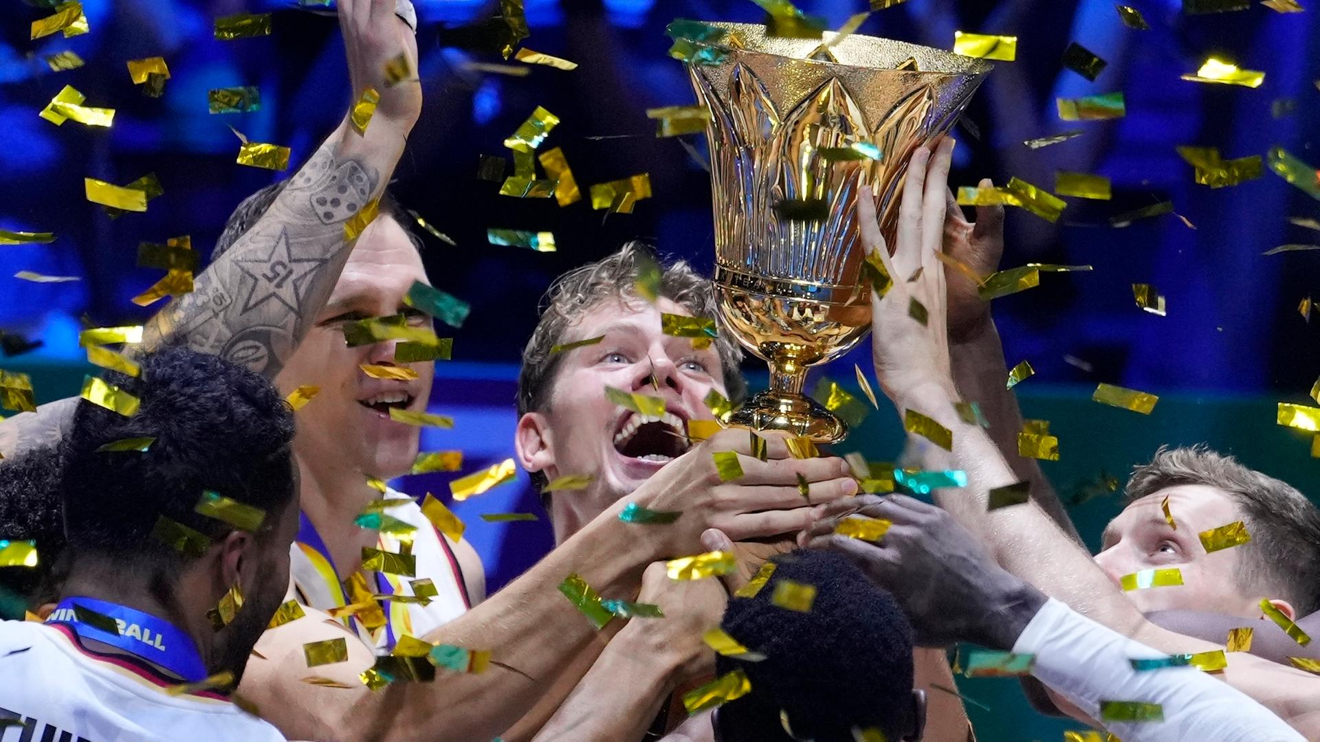 Die deutschen Spieler halten den Pokal in die Höhe. Um sie herum fliegt goldenes Konfetti.