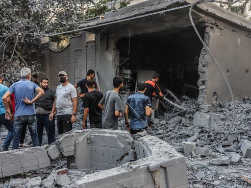 Menschen vor zerstörten Gebäuden in Gaza-Stadt
