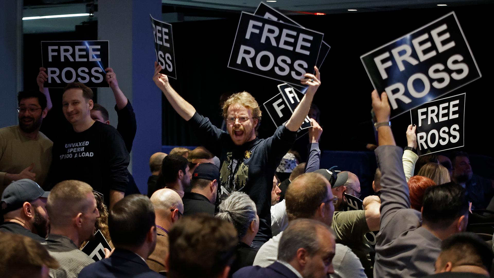 Mitglieder der Libertarian Party stehen auf Stühlen und halten Schilder mit der Aufschrift "Free Ross"