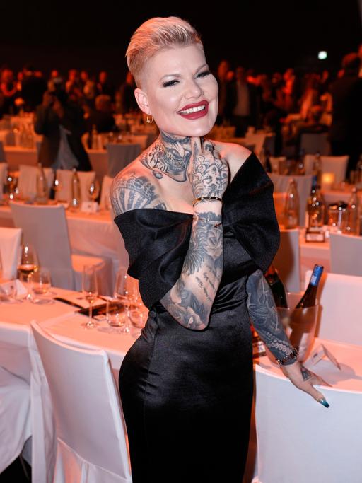 Melanie Müller in einem schwarzen Abendkleid. Sie schaut in die Kamera und lacht.