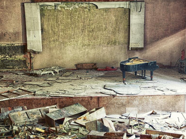 In einem zerstörten Konzersaal nahe Kiew ist auf einer verwüsteten Bühne ein demolierter Flügel zu sehen. 