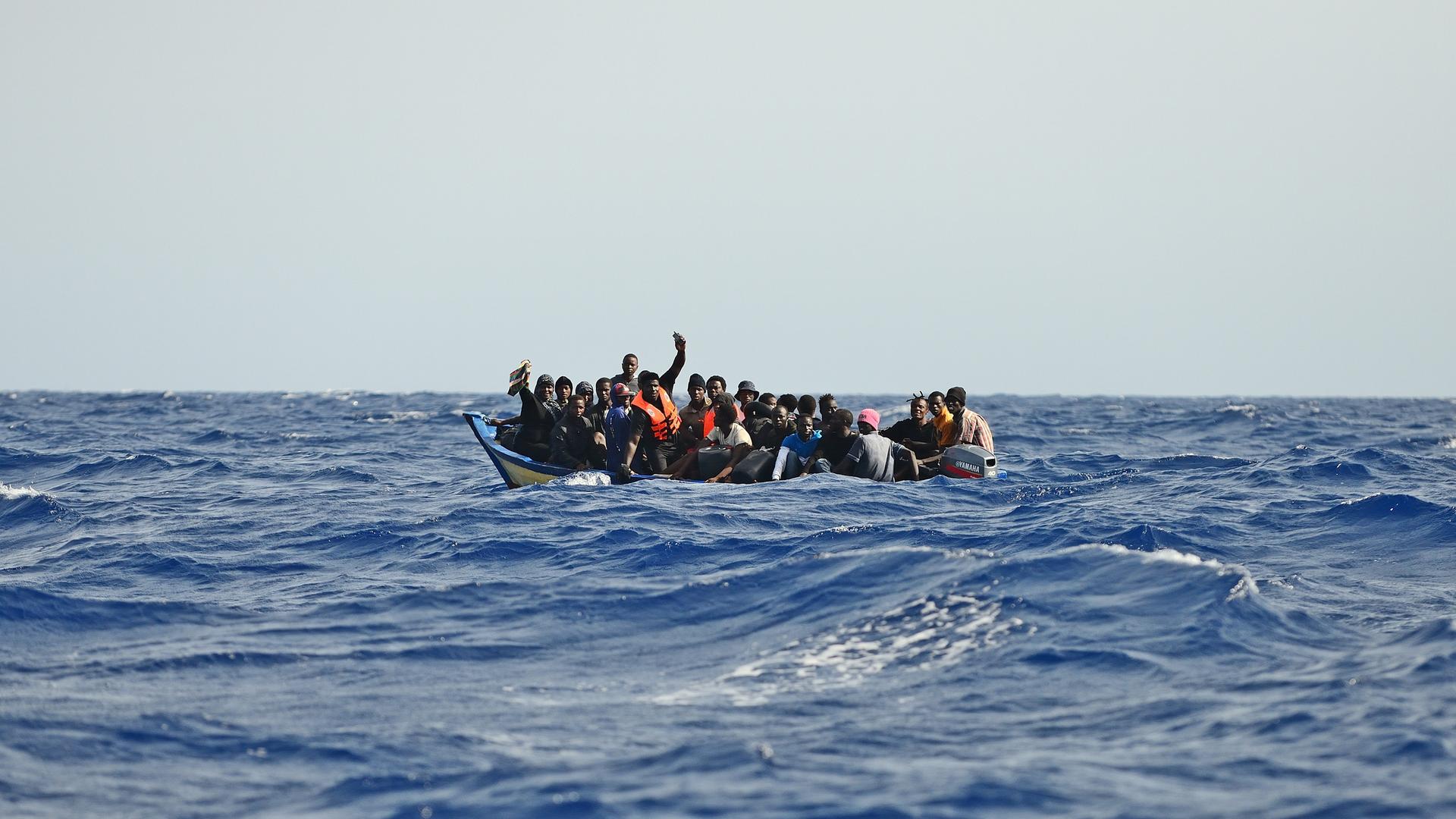 Ein Holzboot mit etwa 30 Menschen versucht bei hohen Wellengang die gefährliche Überfahrt nach Italien. 