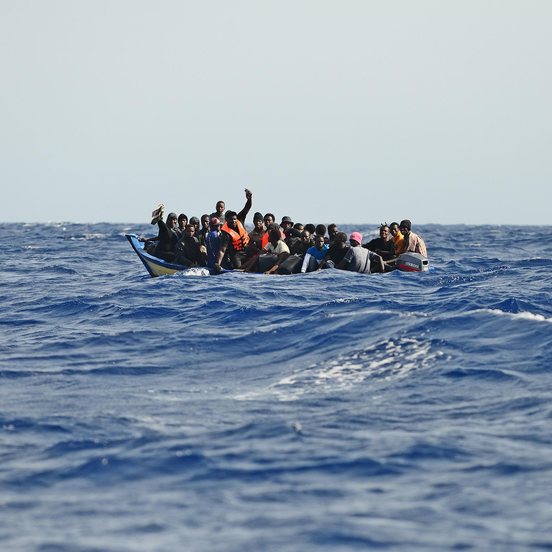 Migration über das zentrale Mittelmeer. Ein Holzboot mit etwa 30 Menschen versucht bei hohen Wellengang die gefährliche Überfahrt nach Italien. Oft geraten diese labilen und überfüllten Boote in Seenot.