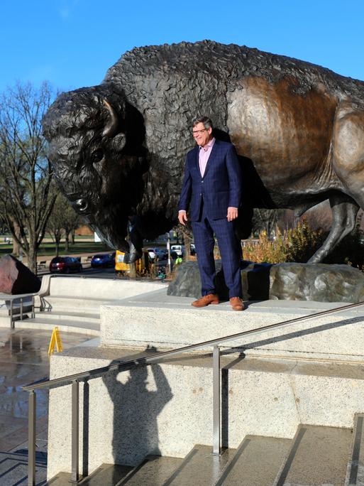 Der Direktor des Smithsonian National Museum of Natural History, Kirk Johnson, lässt sich vor einer der drei bronzenen Bison-Skulpturen fotografieren.