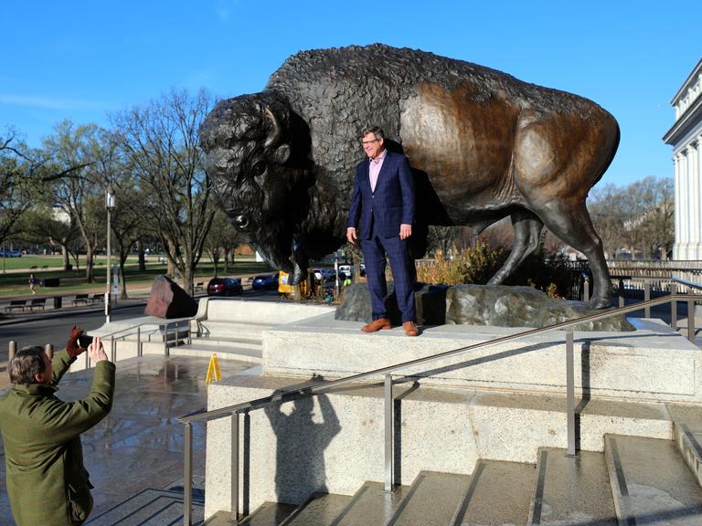 Der Direktor des Smithsonian National Museum of Natural History, Kirk Johnson, lässt sich vor einer der drei bronzenen Bison-Skulpturen fotografieren.