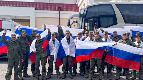 Soldaten mit russischen Fahnen stehen vor einem Bus. 