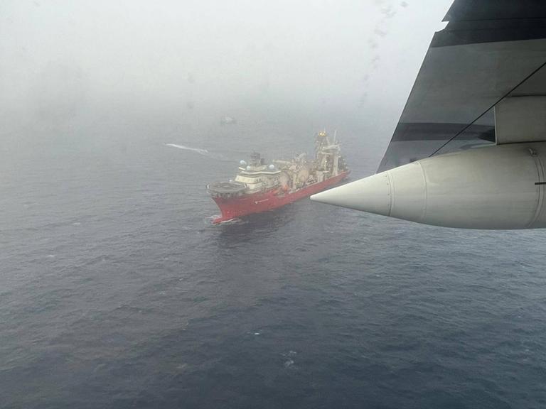 Ein Flugzeug fliegt über ein Suchschiff auf dem Nordatlantik.