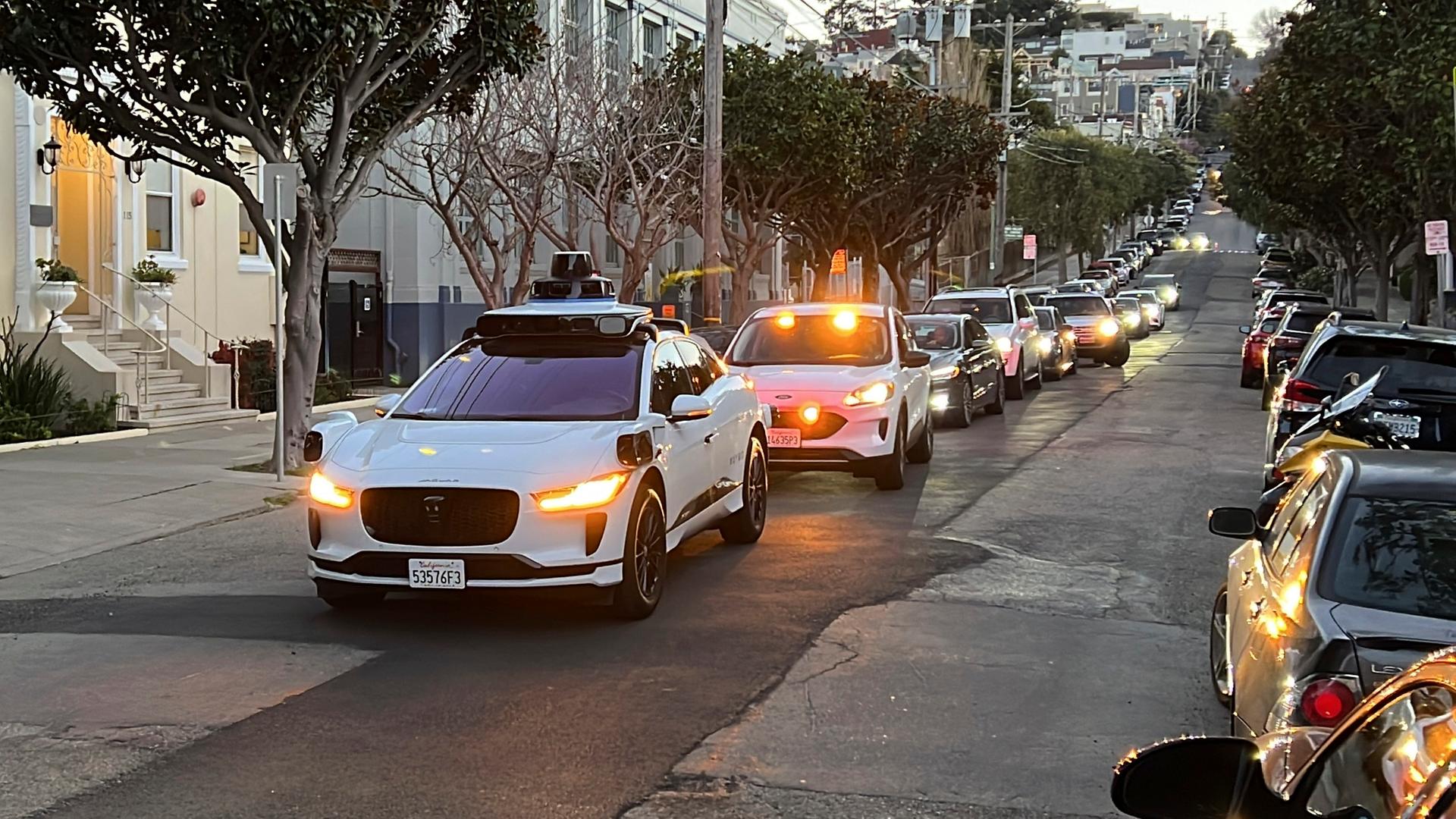 Ein fahrerloses Waymo-Taxi hält auf einer Straße in San Francisco an während sich der Verkehr dahinter staut.