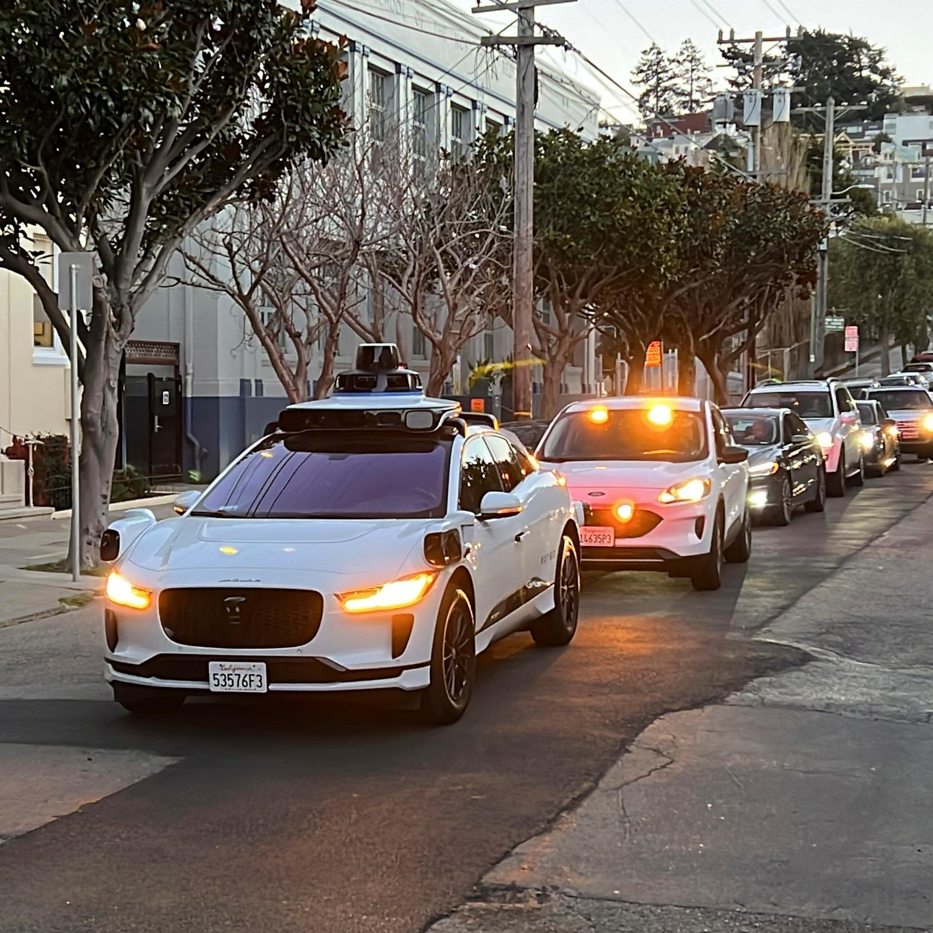 Ein fahrerloses Waymo-Taxi hält auf einer Straße in San Francisco an während sich der Verkehr dahinter staut.