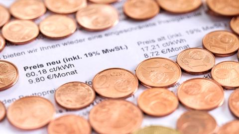 Zahlreiche Cent-Münzen liegen auf einer Stromrechnung. 