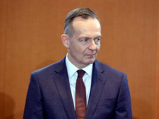 Dr. Volker Wissing, Bundesminister für Digitales und Verkehr, fotografiert vor holzfarbener Wand. Er blickt zum rechten Bildrand.