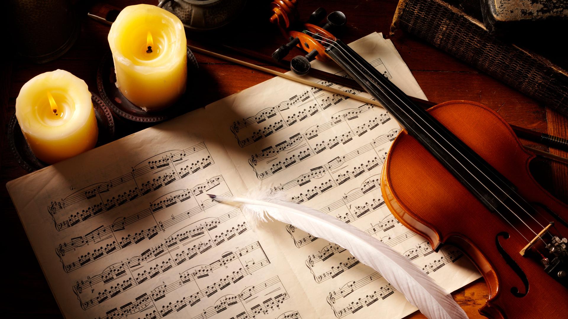 Violine auf Notenblättern mit Feder, von Kerzen illuminiert