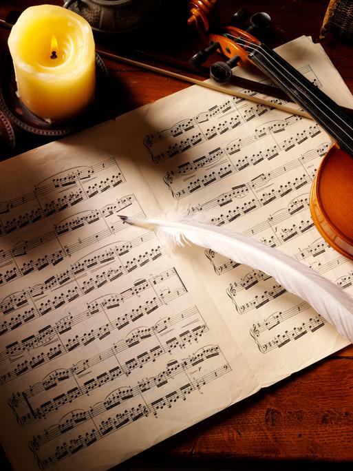 Violine auf Notenblättern mit Feder, von Kerzen illuminiert