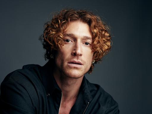 Studioporträt von Daniel Donskoy vor dunkelgrauem Hintergrund.