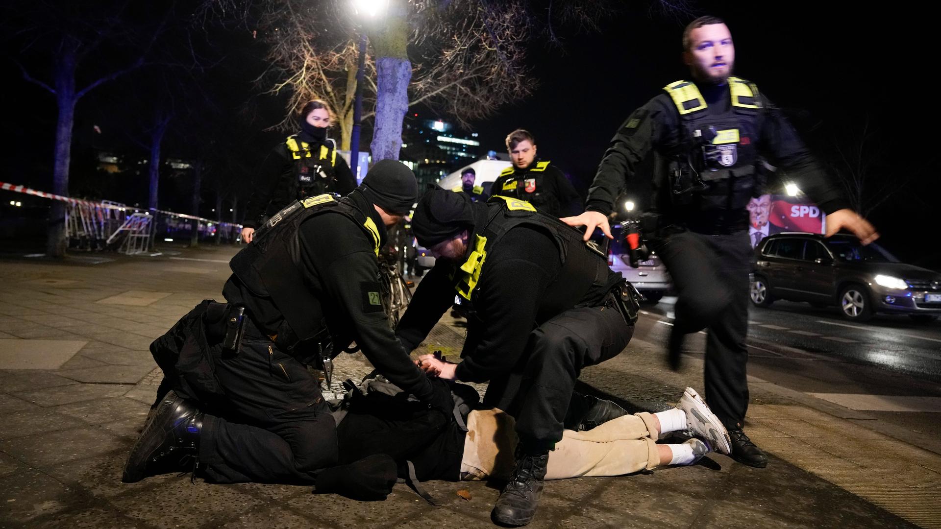 Polizeibeamte sichern einen auf dem Boden liegenden Mann.