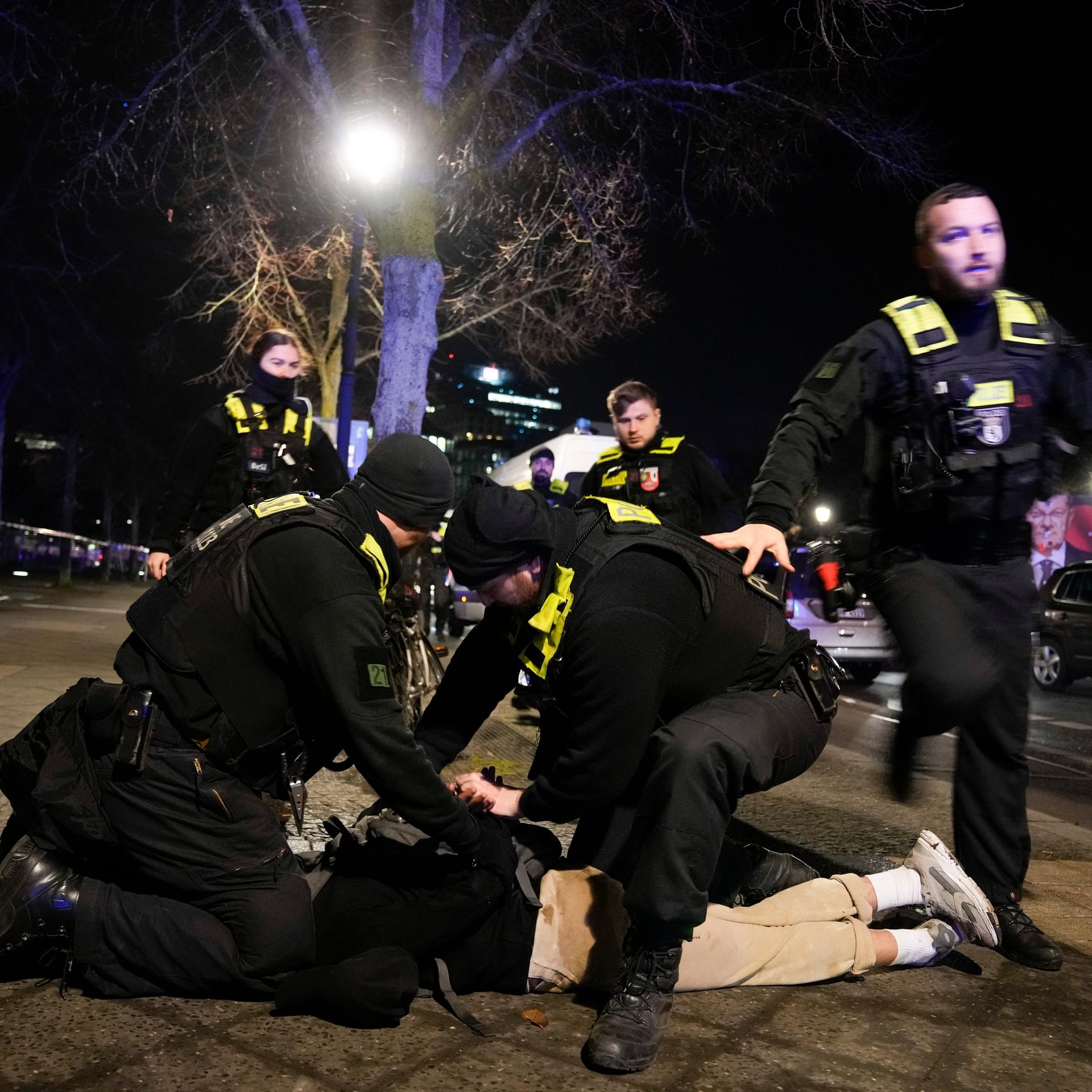 Polizeibeamte sichern einen auf dem Boden liegenden Mann.
