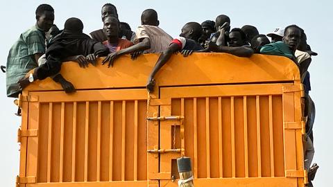 Auf der Ladefläche eines Lastwagen drängen sich zahlreiche Menschen.