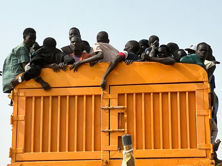 Auf der Ladefläche eines Lastwagen drängen sich zahlreiche Menschen.