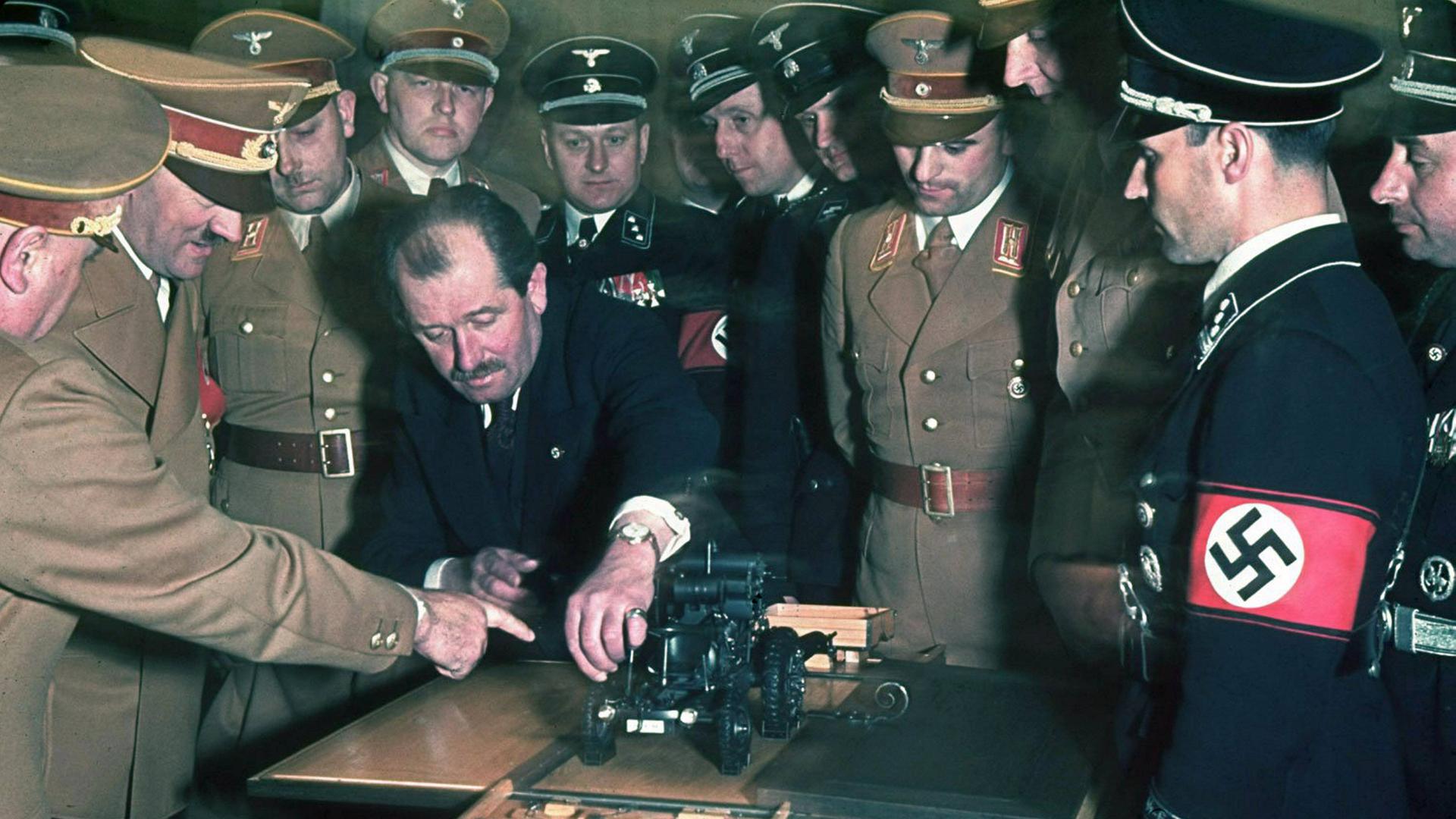 Ferdinand Porsche (1875-1951) zeigt auf ein Automodell, mehrere Männer stehen in Uniformen um ihn herum, darunter Hitler Ferdinand Porsche (1875-1951) zeigt auf ein Automodell, mehrere Männer stehen in Uniformen um ihn herum, darunter Hitler