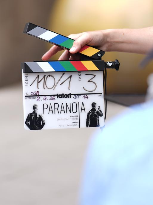 Eine Mitarbeiterin hält eine Filmklappe vor einer Kamera am Set des neuen NDR-Tatort "Paranoia" vor dem Hotel Fraser Suites. Der Krimi soll voraussichtlich in der zweiten Jahreshälfte 2027 in der ARD ausgestrahlt werden. Eine Mitarbeiterin hält eine Filmklappe vor einer Kamera am Set des neuen NDR-Tatort "Paranoia" vor dem Hotel Fraser Suites. Der Krimi soll voraussichtlich in der zweiten Jahreshälfte 2027 in der ARD ausgestrahlt werden.