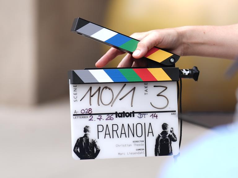 Eine Mitarbeiterin hält eine Filmklappe vor einer Kamera am Set des neuen NDR-Tatort "Paranoia" vor dem Hotel Fraser Suites. Der Krimi soll voraussichtlich in der zweiten Jahreshälfte 2027 in der ARD ausgestrahlt werden. Eine Mitarbeiterin hält eine Filmklappe vor einer Kamera am Set des neuen NDR-Tatort "Paranoia" vor dem Hotel Fraser Suites. Der Krimi soll voraussichtlich in der zweiten Jahreshälfte 2027 in der ARD ausgestrahlt werden.