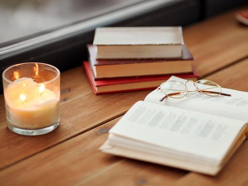 Bücher liegen auf einem Holztisch in einem Raum. 