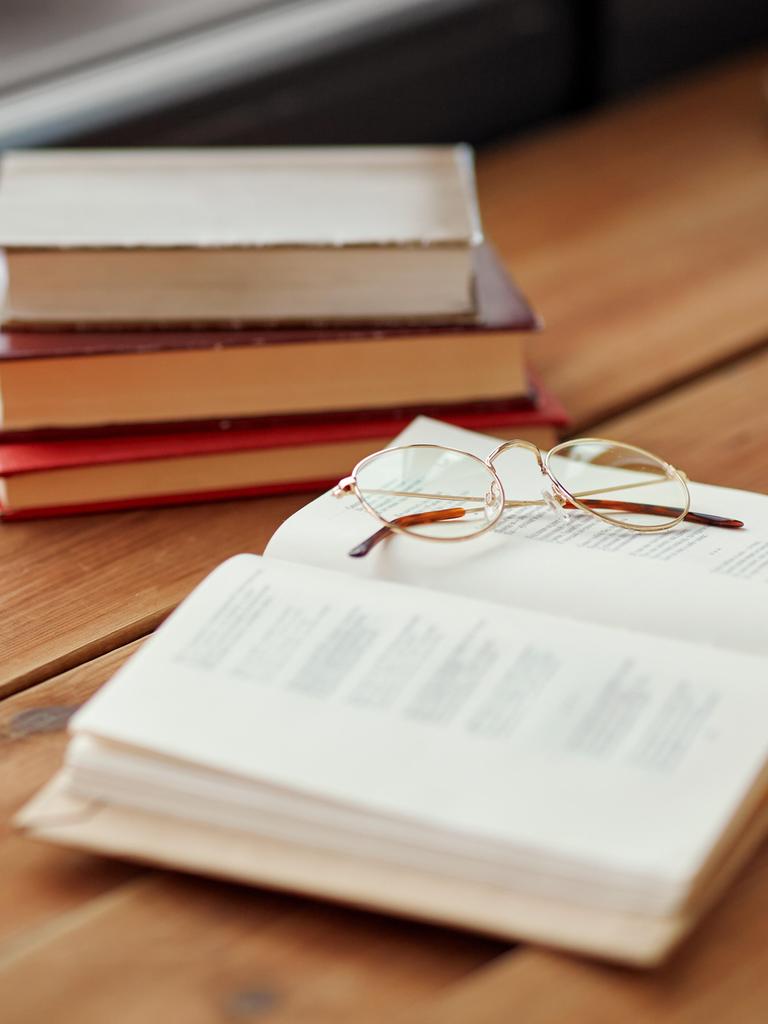 Bücher liegen auf einem Holztisch in einem Raum. 