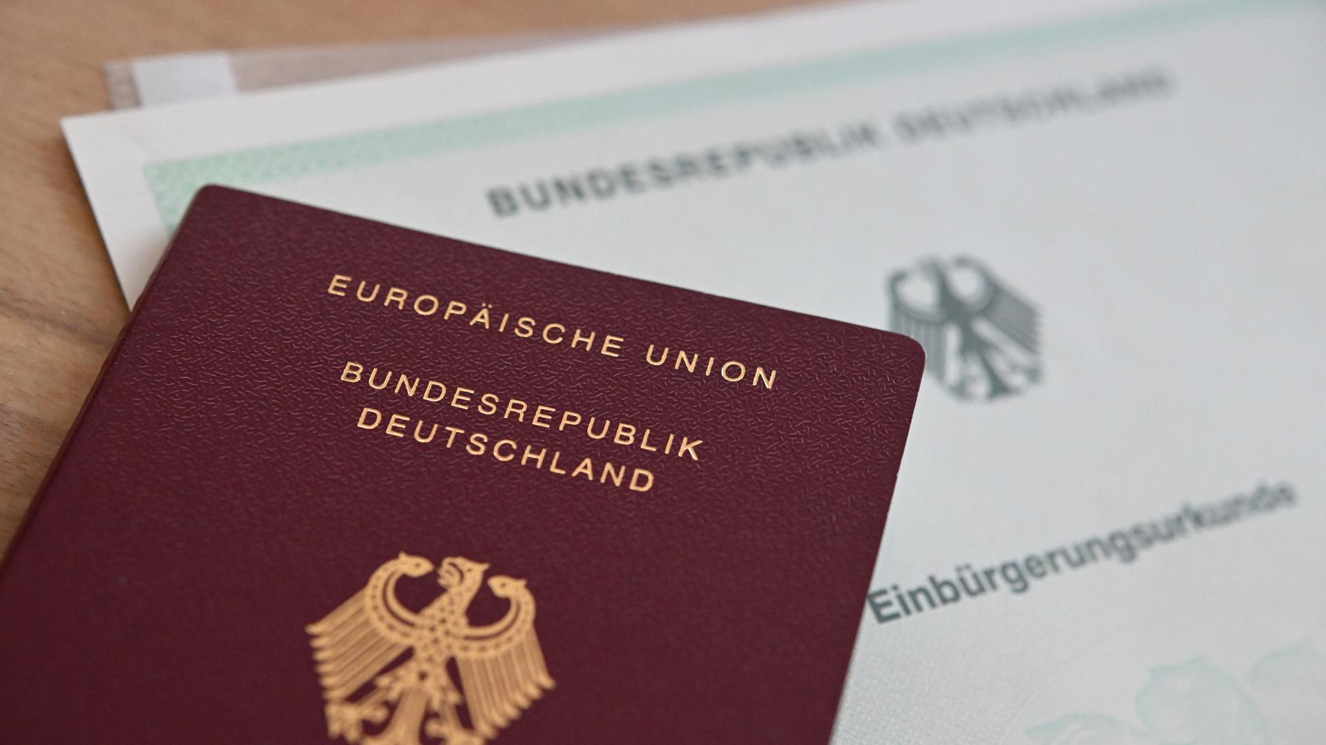 Ein deutscher Reisepass und eine Einbürgerungsurkunde liegen auf einem Tisch.