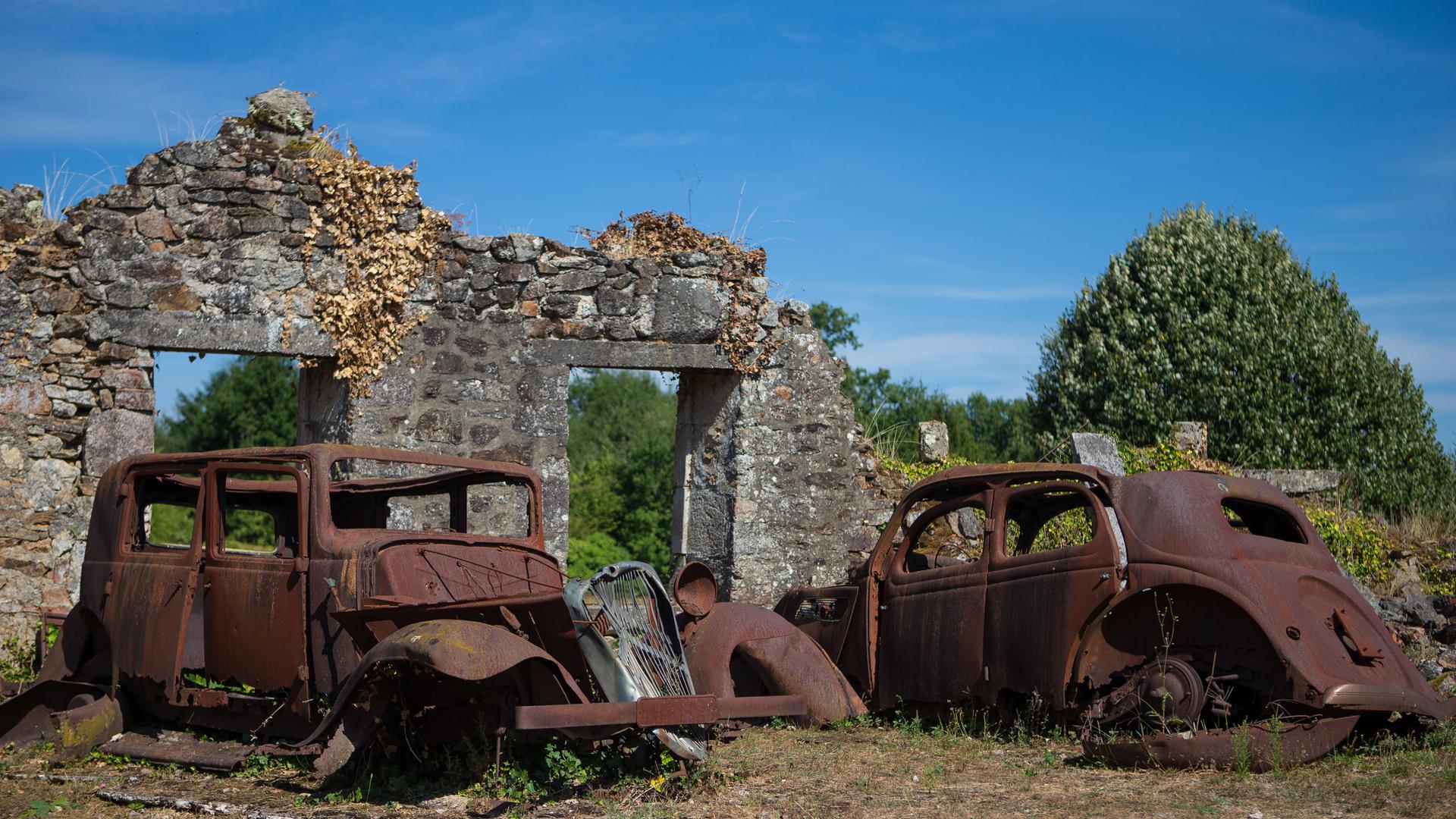 Ausgebrannte Autos stehen vor den Ruinen eines französischen Dorfes.