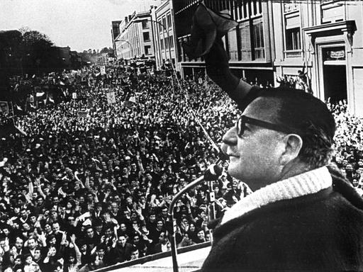 Schwarz-Weiß-Bild: Der damalige Präsident Chiles, Salvador Allende, steht auf einer Rednertribüne unter freiem Himmel, vor ihm eine große Menschenmenge. Geschätztes Aufnahmedatum: August 1973.