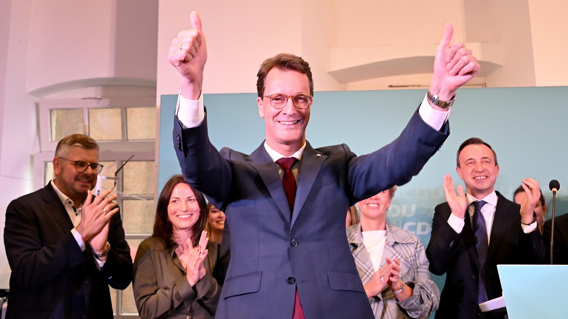Der nordrhein-westfälische CDU-Politiker Hendrik Wüst hebt die Arme nach seinem Statement und lässt sich feiern.