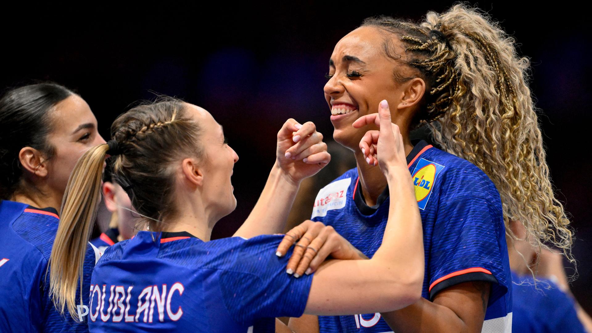 Zu sehen sind drei Spielerinnen der französischen Handball-Nationalmannschaft. Sie lächeln.