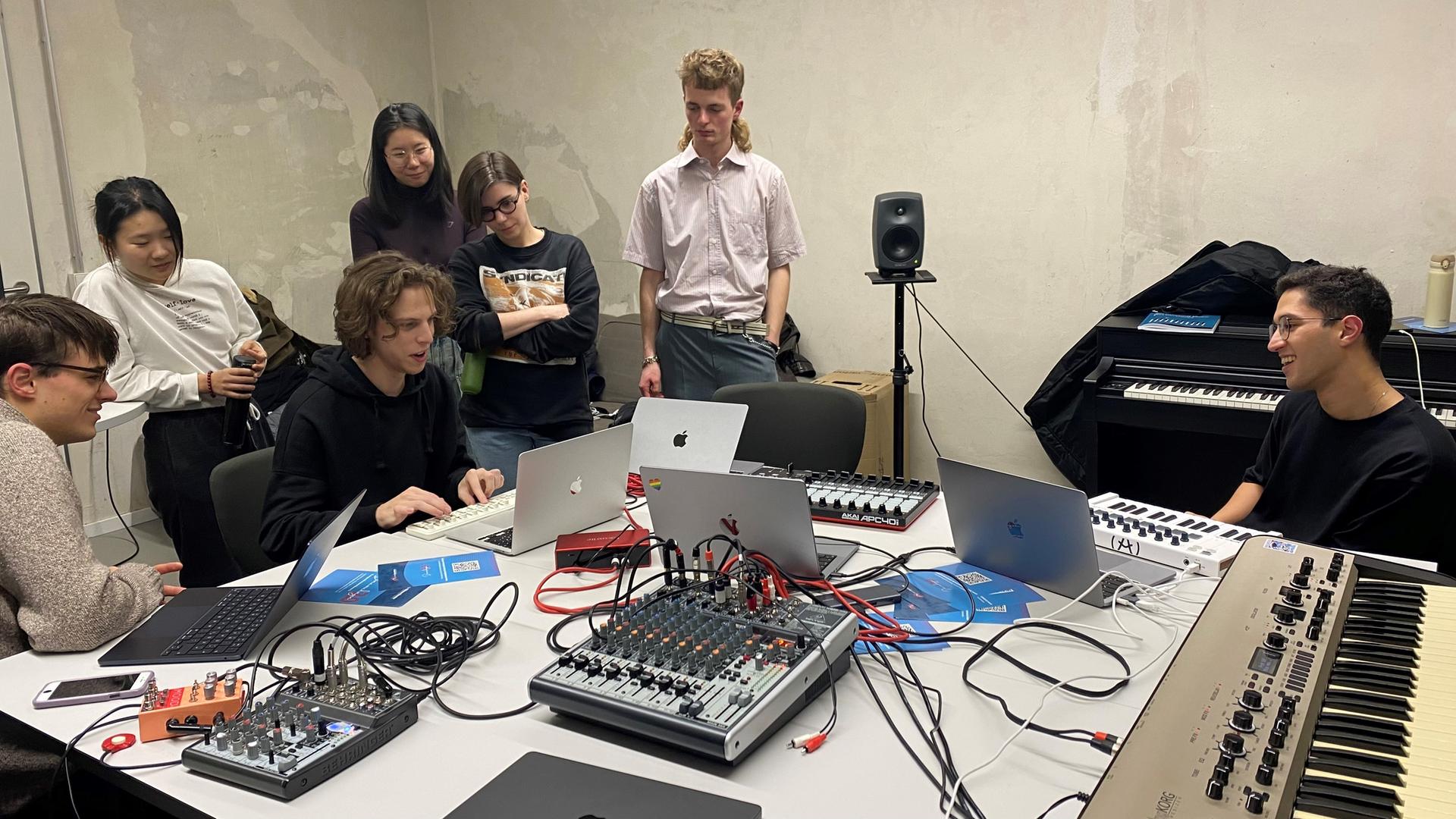 Studierende der Stuttgarter Kompositionsklasse sitzen zusammen um einen Tisch mit elektronischen Gerätschaften Studierende der Stuttgarter Kompositionsklasse sitzen zusammen um einen Tisch mit elektronischen Gerätschaften