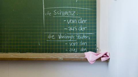 Tafel in einer Sprachschule auf der verschiedene Deklinationen von verschiedenen Ländern geschrieben stehen.