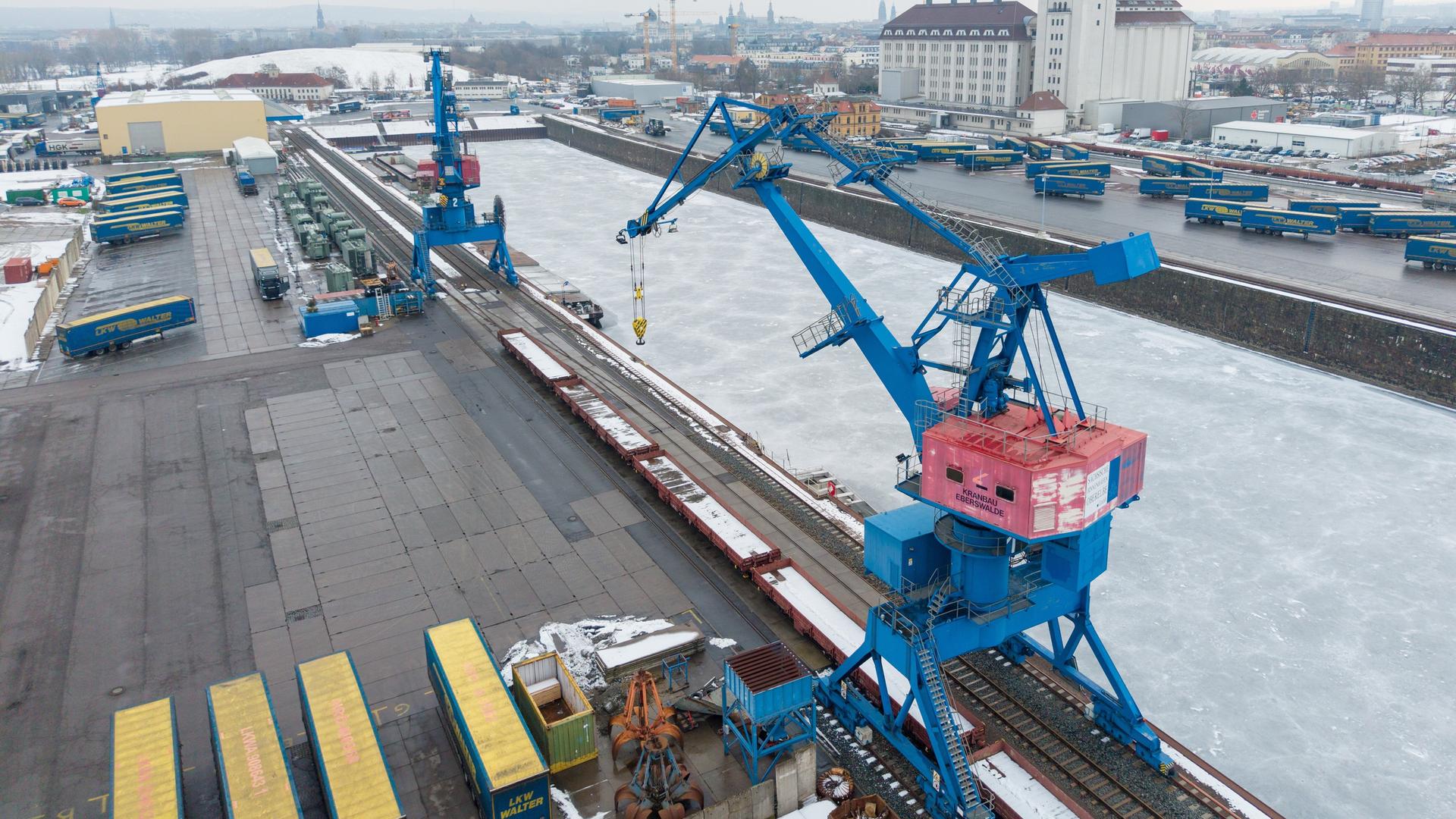 Kräne zur Be- und Entladung stehen im Alberthafen vor dem mit Eis bedeckten Hafenbecken.