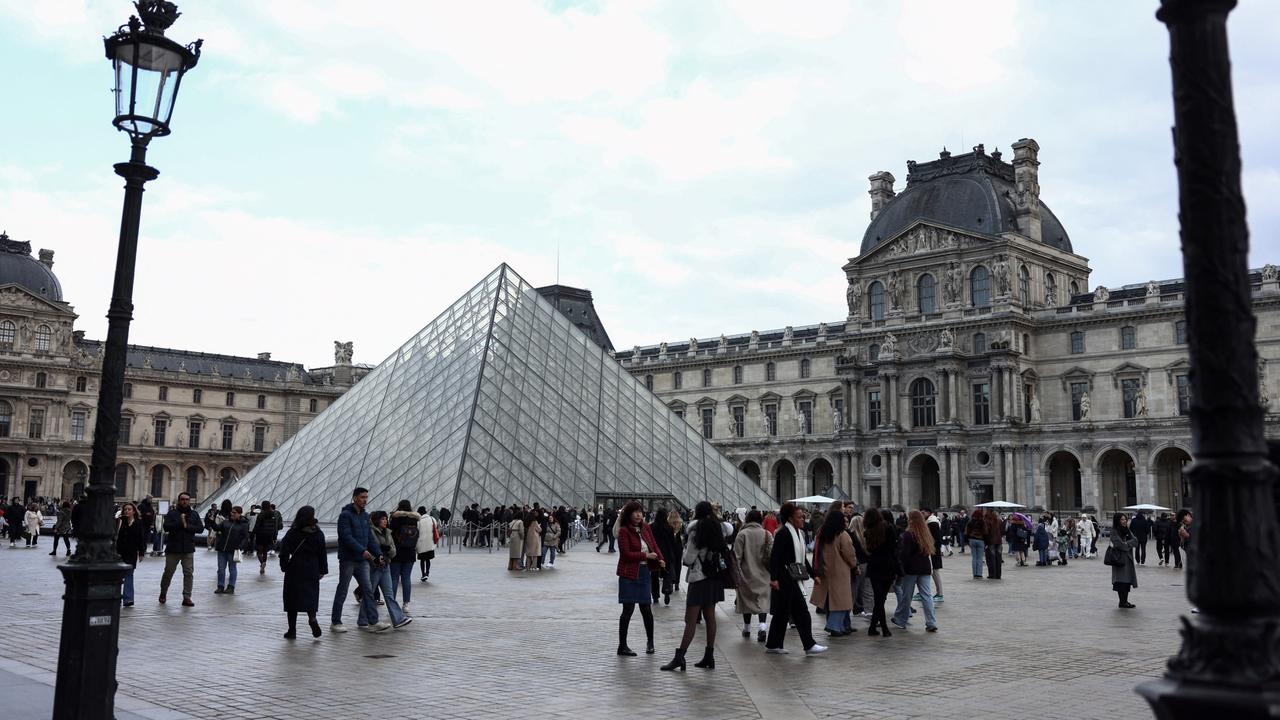 In der Nähe der Louvre-Pyramide flanieren Touristen in Paris.