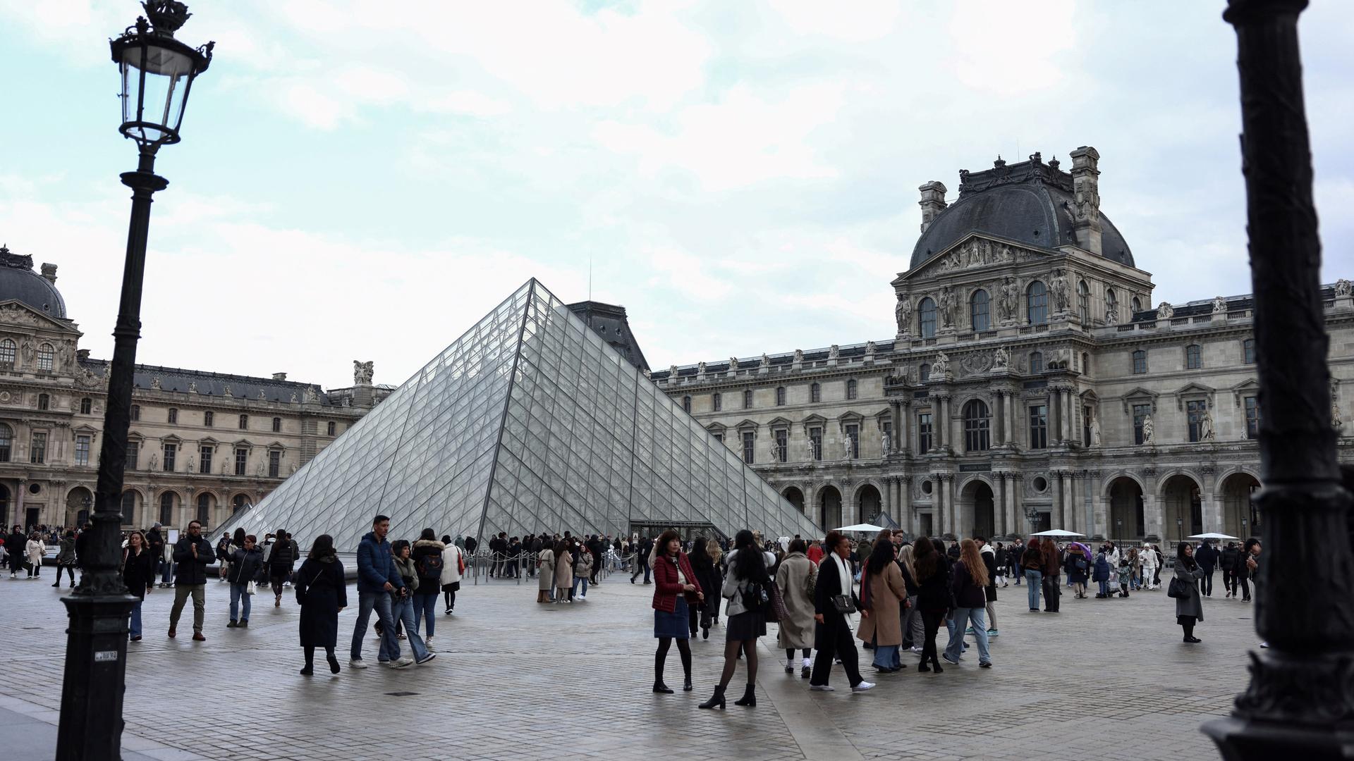 In der Nähe der Louvre-Pyramide, die vom chinesisch-amerikanischen Architekten Ming Pei entworfen wurde, flanieren Touristen am 28. Februar 2025 in Paris. In der Nähe der Louvre-Pyramide, die vom chinesisch-amerikanischen Architekten Ming Pei entworfen wurde, flanieren Touristen am 28. Februar 2025 in Paris.