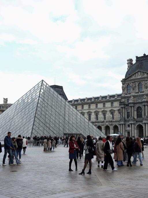 In der Nähe der Louvre-Pyramide, die vom chinesisch-amerikanischen Architekten Ieoh Ming Pei entworfen wurde, flanieren Touristen am 28. Februar 2025 in Paris.