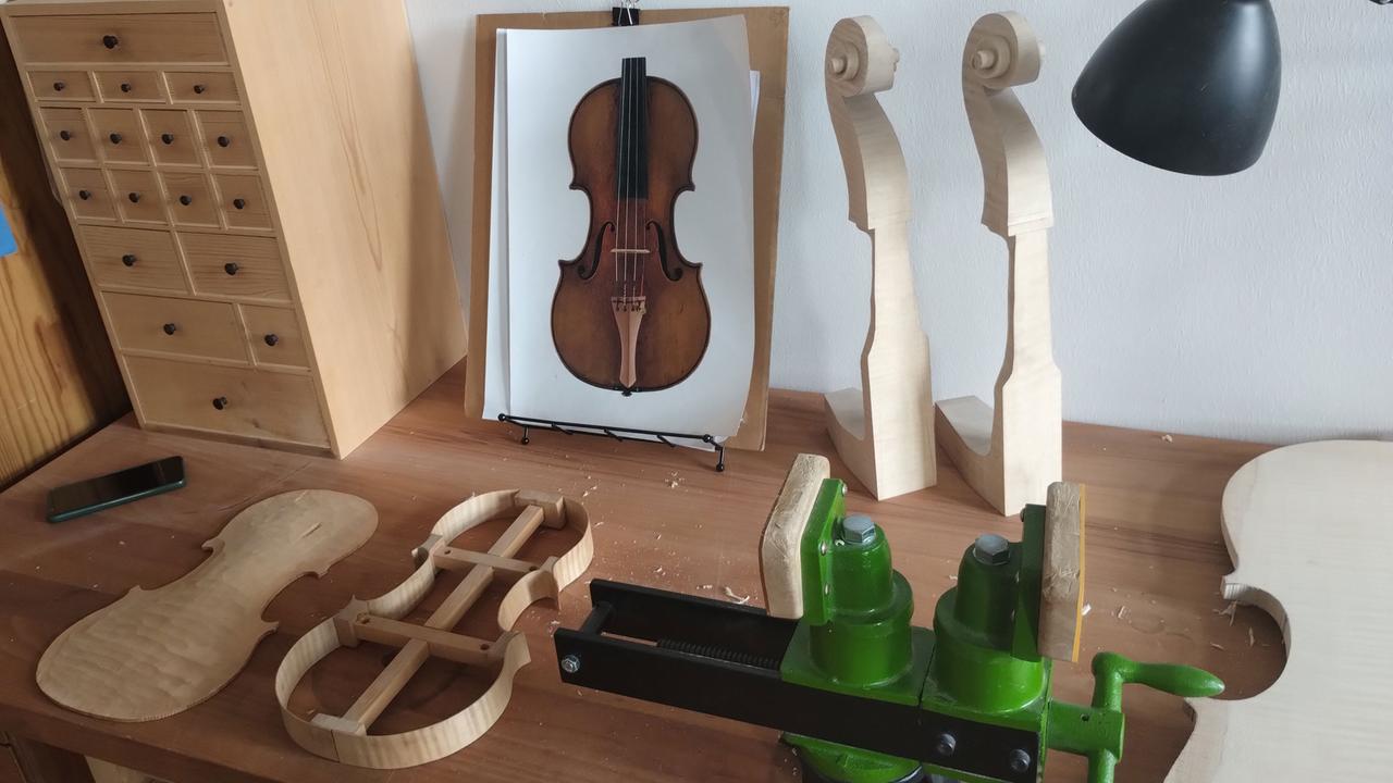 Tischlerbank, Schraubzwinge und eine ausgestanzte Geige in der Geigenbauwerkstatt von Mira Gruszow und Gideon Baumblatt in Werder (Brandenburg).