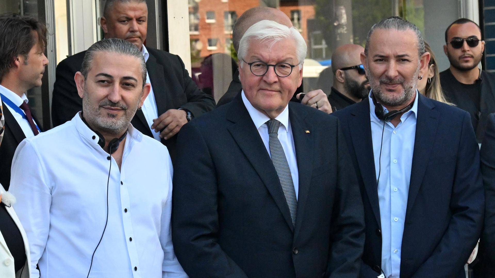 Zu sehen ist Bundespräsident Steinmeier beim Besuch in Köln. Links und rechts von ihm stehen die beiden Besitzer eines Friseurgeschäfts. Zu sehen ist Bundespräsident Steinmeier beim Besuch in Köln. Links und rechts von ihm stehen die beiden Besitzer eines Friseurgeschäfts.